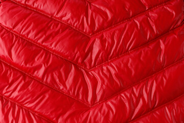 Texture of quilted red down jacket or coat as background.