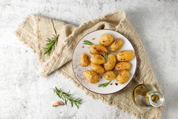 Fresh baked potatoes with olive oil, rosemary and garlic on vintage plate over linen towel.