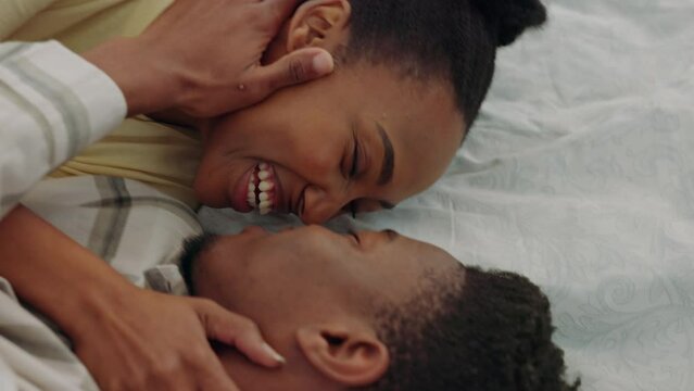 Excited, kiss and couple jump on a bed in their house for sleep, peace and relax together. Happy, content and African man and woman with love, affection and smile while kissing in the bedroom