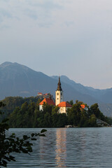 Church in the middle of lake bled in Slovenia at the golden hour with mountains in the background
