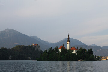 Church in the middle of lake bled in Slovenia at the golden hour with mountains in the background 