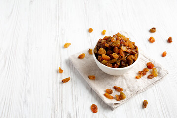 Organic Dried Raisins in a White Bowl, side view. Space for text.