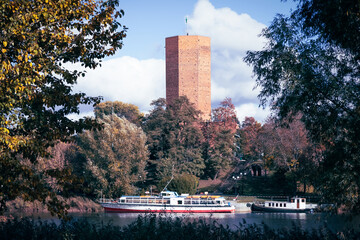 Kruszwica, Poland - famous medieval Mice Tower and a sightseeing cruise ship on Lake Goplo in autumn