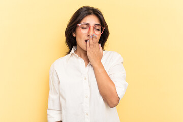 Young Indian woman isolated on yellow background yawning showing a tired gesture covering mouth with hand.