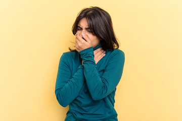 Young Indian woman isolated on yellow background suffers pain in throat due a virus or infection.