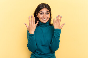 Young Indian woman isolated on yellow background showing number ten with hands.