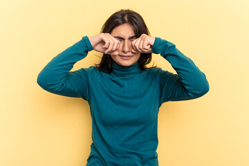 Young Indian woman isolated on yellow background whining and crying disconsolately.