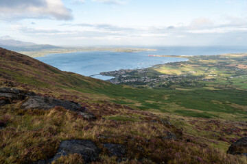 View from the top on fields in many shades of green in a valley in the Irish rural countryside. Bay and sea in the background