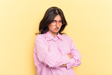 Fototapeta premium Young Indian woman isolated on yellow background frowning face in displeasure, keeps arms folded.