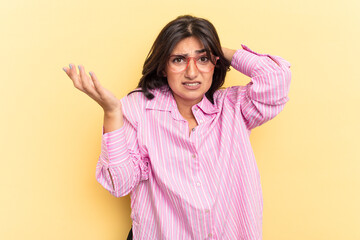 Young Indian woman isolated on yellow background screaming with rage.