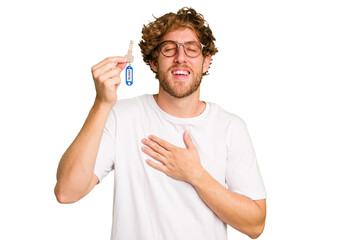 Young caucasian man holding home keys isolated on white background laughs out loudly keeping hand on chest.