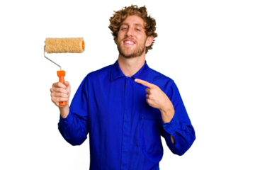 Young painter man holding a roll isolated on white background smiling and pointing aside, showing something at blank space.