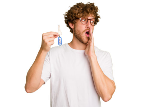 Young caucasian man holding home keys isolated on white background is saying a secret hot braking news and looking aside