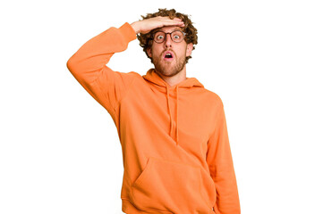 Young caucasian man isolated on green chroma background looking far away keeping hand on forehead.
