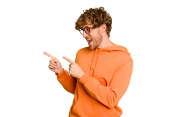 Young caucasian man isolated on green chroma background points with thumb finger away, laughing and carefree.