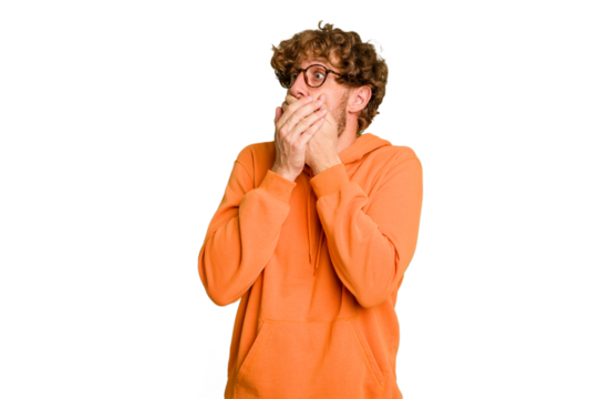 Young caucasian man isolated on green chroma background thoughtful looking to a copy space covering mouth with hand.