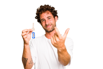 Young caucasian man holding home keys isolated pointing with finger at you as if inviting come closer.
