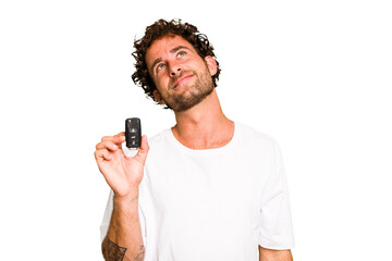 Young caucasian man holding car keys isolated dreaming of achieving goals and purposes