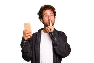 Young caucasian man using mobile phone isolated keeping a secret or asking for silence.