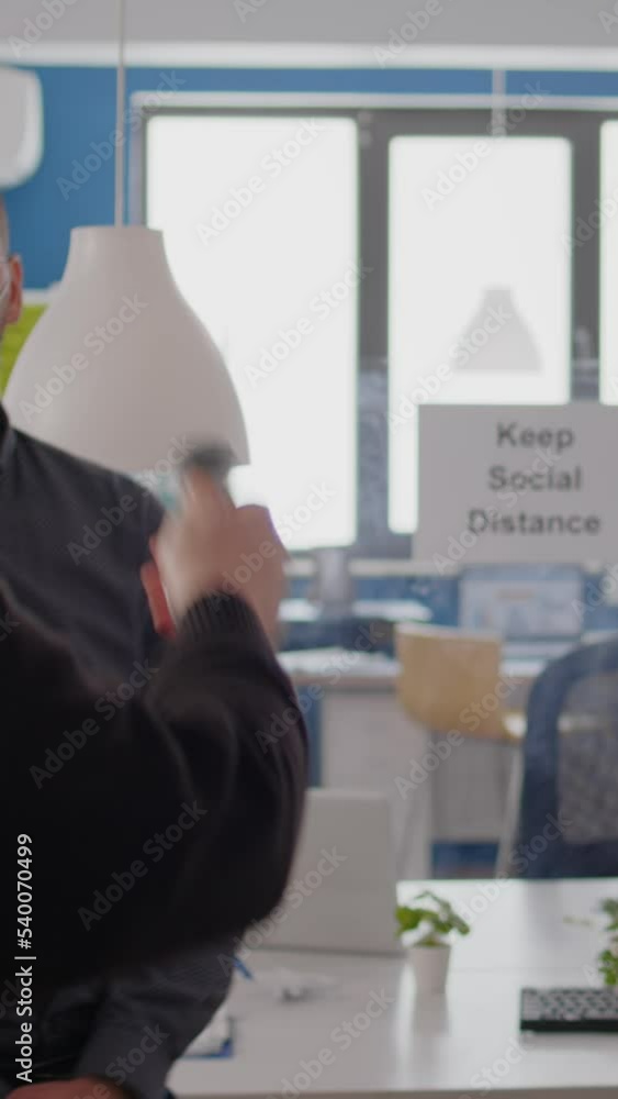 Poster vertical video business man with protective face mask checking collegues temperature using infrared 
