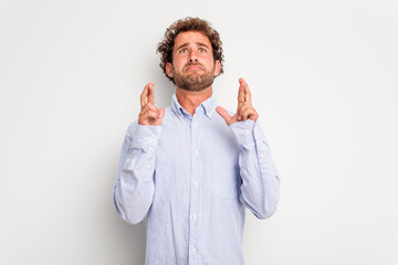 Young caucasian curly hair man isolated on white background crossing fingers for having luck