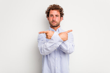 Young caucasian curly hair man isolated on white background points sideways, is trying to choose between two options.