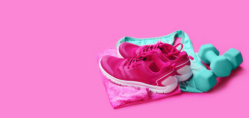 still life with pink sneakers, green dumbbells laying on sportive shirts
