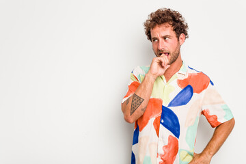 Young caucasian curly hair man isolated on white background relaxed thinking about something looking at a copy space.