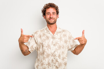Naklejka premium Young caucasian curly hair man isolated on white background person pointing by hand to a shirt copy space, proud and confident