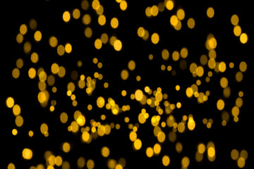 Fototapeta na wymiar Abstract gold glitter, unfocused, isolated on a black background for overlay design. Golden blurred bokeh light. Photo.