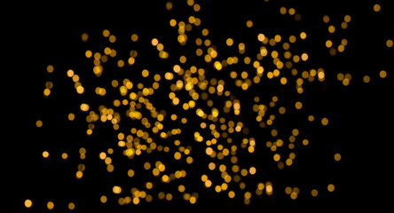 Abstract gold glitter, defocused image highlighted on a black background for overlay design. Golden...