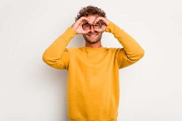 Young caucasian curly hair man isolated on white background showing okay sign over eyes