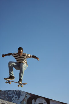 Portrait of young non-binary doing flip tricks on skateboard at skatepark