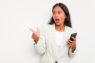 Fototapeta premium Young business Indian woman holding a mobile phone isolated on white background pointing to the side