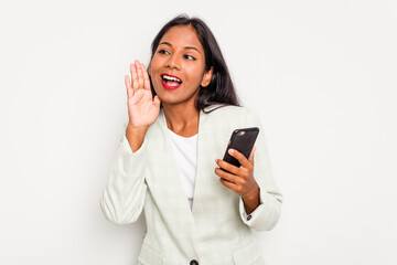 Fototapeta premium Young business Indian woman holding a mobile phone isolated on white background shouting and holding palm near opened mouth.