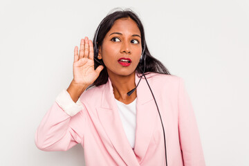 Telemarketer Indian woman working with a headset isolated on white background trying to listening a gossip.