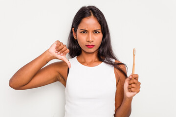 Young Indian woman brushing teeth isolated on white background showing a dislike gesture, thumbs...