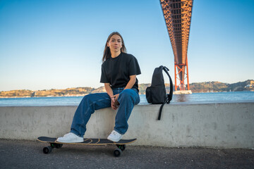 Female teenager looking at the camera and sitting with her skateboard