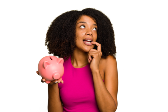 Young African American woman holding a piggy bank isolated relaxed thinking about something looking at a copy space. - Powered by Adobe
