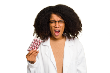 Young pharmacist African American woman holding a tablet of pills isolated screaming very angry and aggressive.