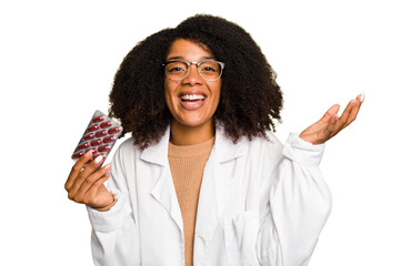 Young pharmacist African American woman holding a tablet of pills isolated receiving a pleasant...