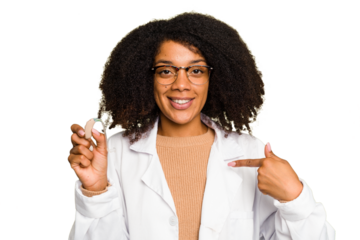 Young otorhinolaryngologist African american woman holding hearing aid isolated person pointing by hand to a shirt copy space, proud and confident