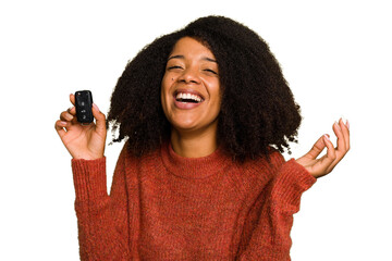 Young African american woman holding car keys isolated receiving a pleasant surprise, excited and...