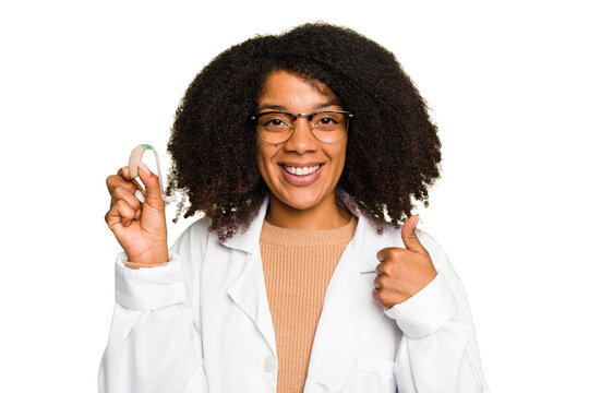 Young otorhinolaryngologist African american woman holding hearing aid isolated smiling and raising thumb up