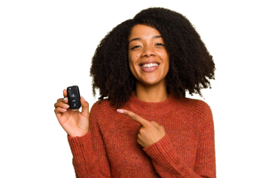 Young African american woman holding car keys isolated smiling and pointing aside, showing something at blank space.