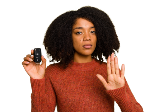 Young African american woman holding car keys isolated standing with outstretched hand showing stop sign, preventing you.