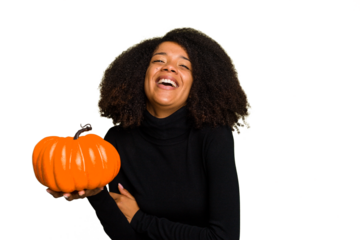 Young African American woman holding a pumpkin for halloween day isolated laughing and having fun.