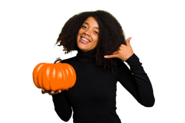 Young African American woman holding a pumpkin for halloween day isolated showing a mobile phone call gesture with fingers.
