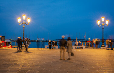 Tourists and locals relaxing and working on the harbour waterfront -Chioggia Venetian Lagoon,...