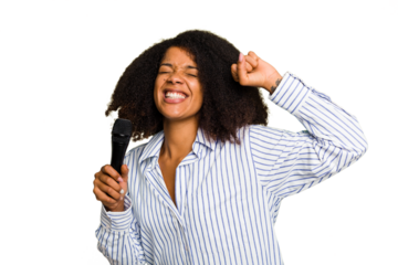 Young African American singer woman holding a microphone isolated raising fist after a victory, winner concept.